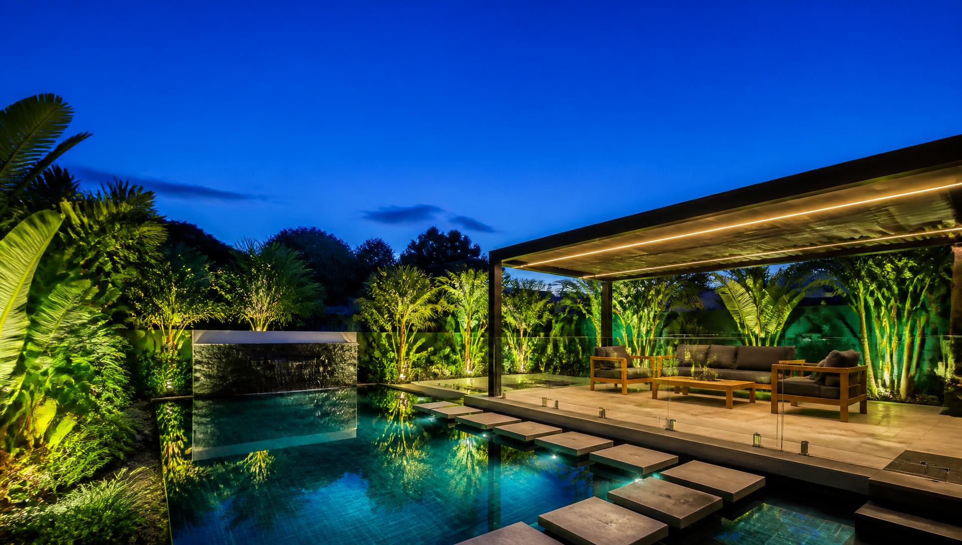 Dramatic infinity edge pool and tropical garden backyard design at sunset